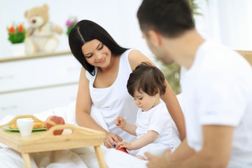 Fototapeta premium Family taking the breakfast on the bed in the bedroom
