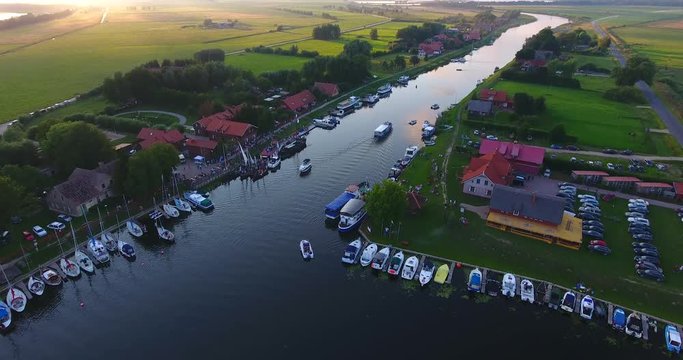 AERIAL: flight over the Minge village marina. Yachts, pier, green fields and small recreational houses around a river - 010