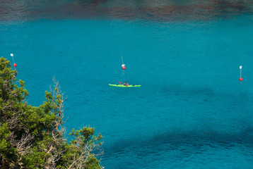 Man on a kayak in the sea of En Porter cove in Menorca