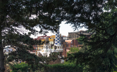 Fototapeta na wymiar View to the fairytale gingerbread lodge with rooftop terrace through pine tree branches in Park Guell, Barcelona, Spain.