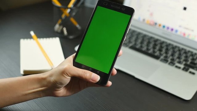 Business woman using a Smart phone Touchscreen CHROMA KEY- Close-up , Fingers make gestures touching and swiping the screen of a modern smartphone. A woman Holds a mobile With Green screen.