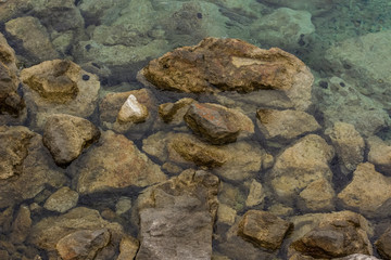calm rest concept of blue water surface and small waves with stones and empty space for copy or text