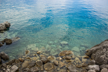 calm rest concept of blue water surface and small waves with stones and empty space for copy or text