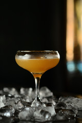 orange cocktail in a glass with ice on a dark background