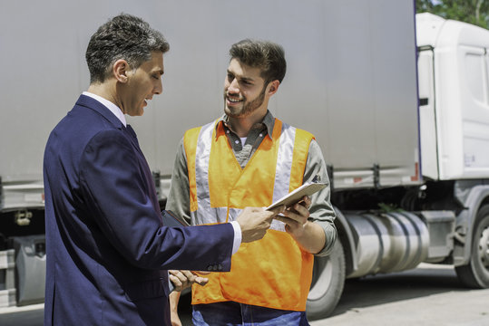 Worker and businessman discussing near lorry