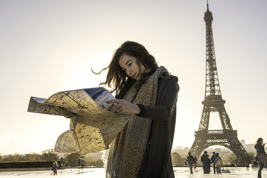 Woman reading map near Eiffel Tower