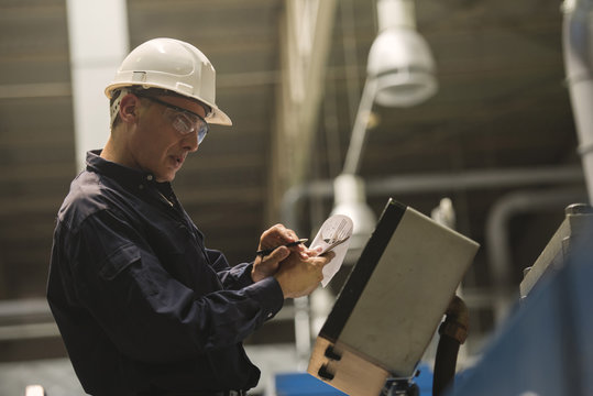 Factory worker examining control panel