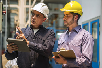 Factory workers examining control panel in factory