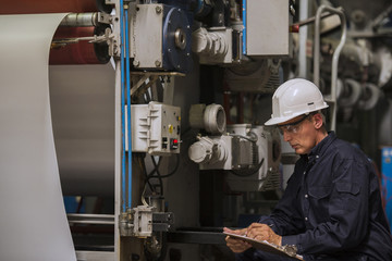 Factory worker writing on clipboard in factory