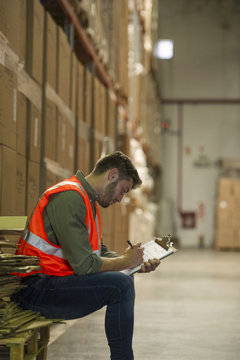 Worker writing on clipboard in warehouse