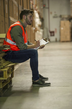 Worker writing on clipboard in warehouse