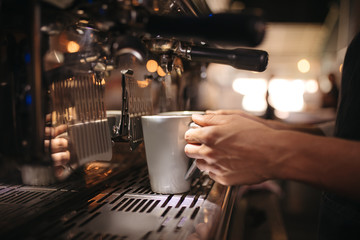 Fototapeta na wymiar Female cafe worker preparing coffee in machine