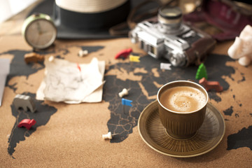 A cup of fragrant coffee on the map, an old camera and a route plan, a vintage photo. Travel and...