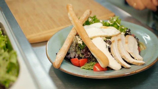 chef puts the grisini on a salad in a restaurant kitchen. cooking salad step by step