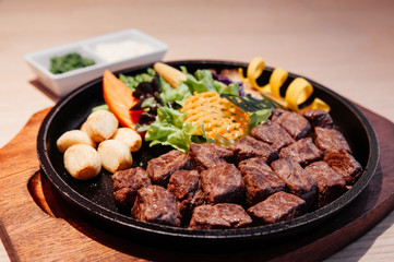 Japanese grilled beef steak Gyu Teppanyaki on hot plate with salad and roasted garlics