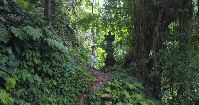 Woman gives respect to temple sculpture in sacred place on the north at nature of Bali island area,Indonesia