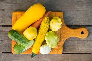 Zucchini, squash, cucumber, carrots in a pink plate on a wooden table. Diet, a healthy lifestyle, healthy foods.