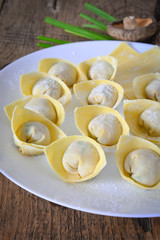 Homemade meat and prawn wonton soup in white bowl on wooden table background.
