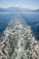 Looking back to the far shore. Wave pattern on the water surface  behind boat.  Montenegro, Bay of Kotor, Adriatic Sea