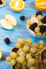 Different fruits and berries on wooden blue table. Ready for summer fruit variety on blue wooden desk. Mixed summer oraganic fruits assortment