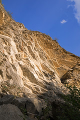 Rocky cliff and clear blue sky. Bright yellow stone and rock