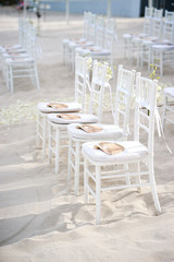 Fototapeta na wymiar The white chiavari chairs setup for modern beach wedding venue with flowers decoration on aisle