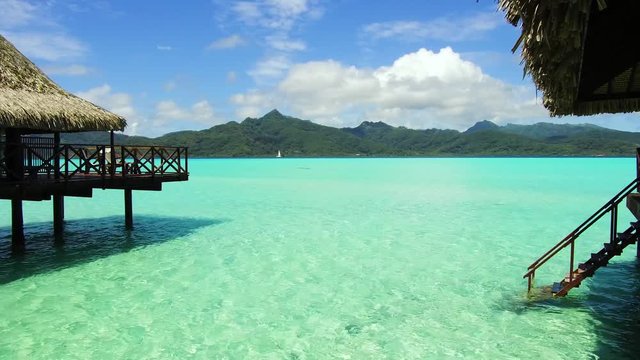 travel, tourism, vacation and summer holidays concept - bungalow huts in sea on tropical resort beach