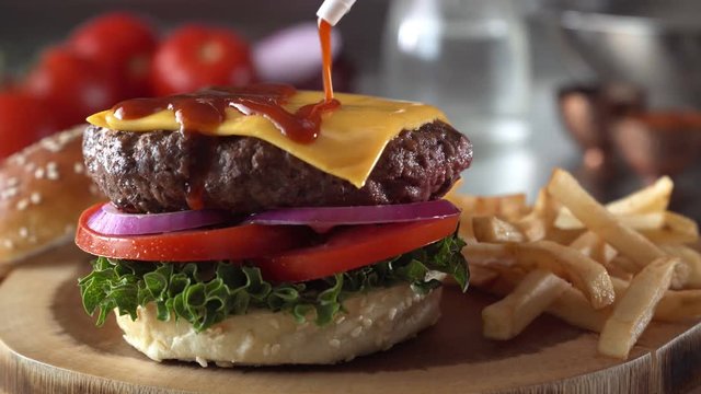 Slider footage of a delicious cheeseburger with bbq sauce being squeezed over the top.