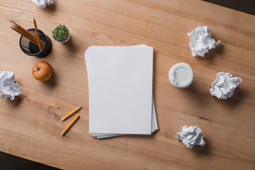 top view of stacked blank papers on wooden table with crumpled papers