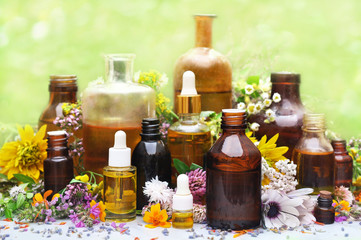 Essential oil bottles on medicinal flowers and herbs background, selective focus