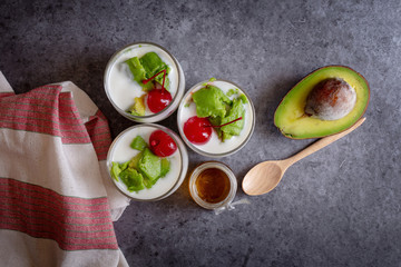 Glass of Cherry and avocado sliced in yogurt on wooden background