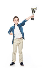 cheerful schoolboy showing winner cup isolated on white
