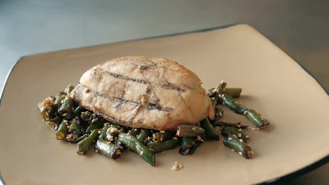 chef puts a piece of roast meat on green beans on a plate in a restaurant. concept of cooking dishes step by step