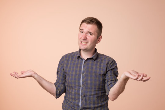 Studio portrait of confused handsome guy showing I have no idea gesture.