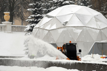 The snow-removing machine clears the city street from snow. snow blower