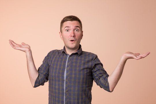 Studio portrait of confused handsome guy showing I have no idea gesture.