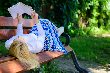 Girl lay bench park relaxing with book, green nature background. Woman spend leisure with book. Interesting book. Smart and pretty. Girl reading outdoors while relaxing on bench. Smart lady relaxing