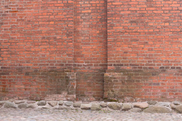 Grunge red brick wall and stone pavement . Urban background