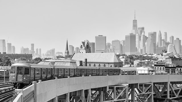 Black and white picture of New York subway train and Manhattan skyline seen from Brooklyn, USA.