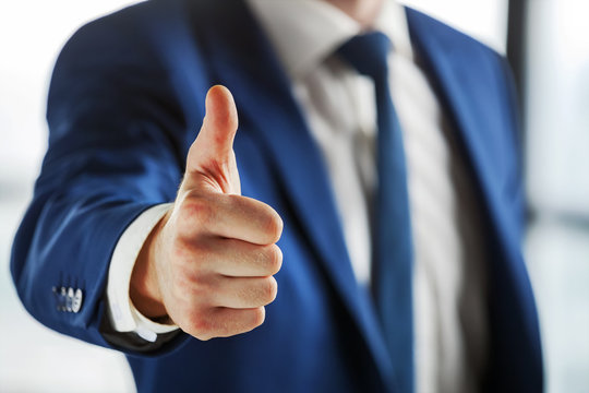 Closeup of business person showing thumb up.