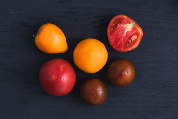 Red, yellow and brown tommato on dark blue wooden background