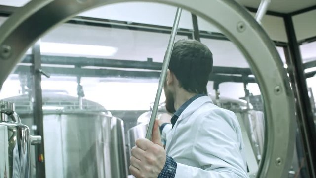 Brewery worker using digital refractometer white testing beer during boiling process at plant