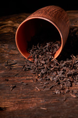 Dry tea in clay cup on wooden table. Selective focus, close up