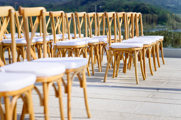 Wooden folding lawn chairs line up for outdoors wedding venue settings, Selective focus on the back row of chairs