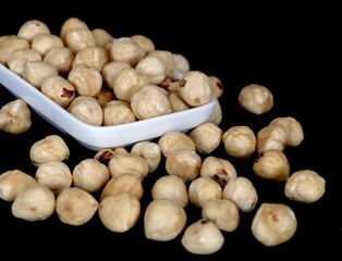 roasted hazelnuts dumped on a black background,
