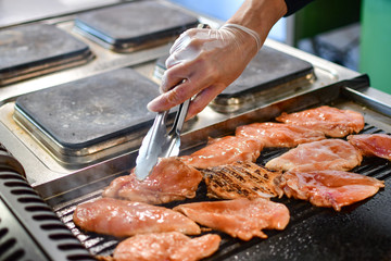 cooking chicken fillet on the grill in a restaurant in Florence, the chef turns the meat with forceps, selective focus