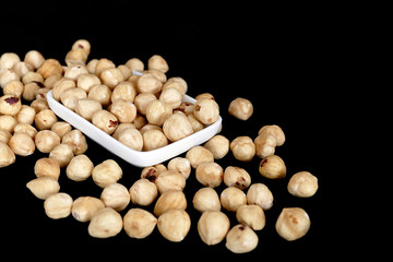 roasted hazelnuts dumped on a black background,
