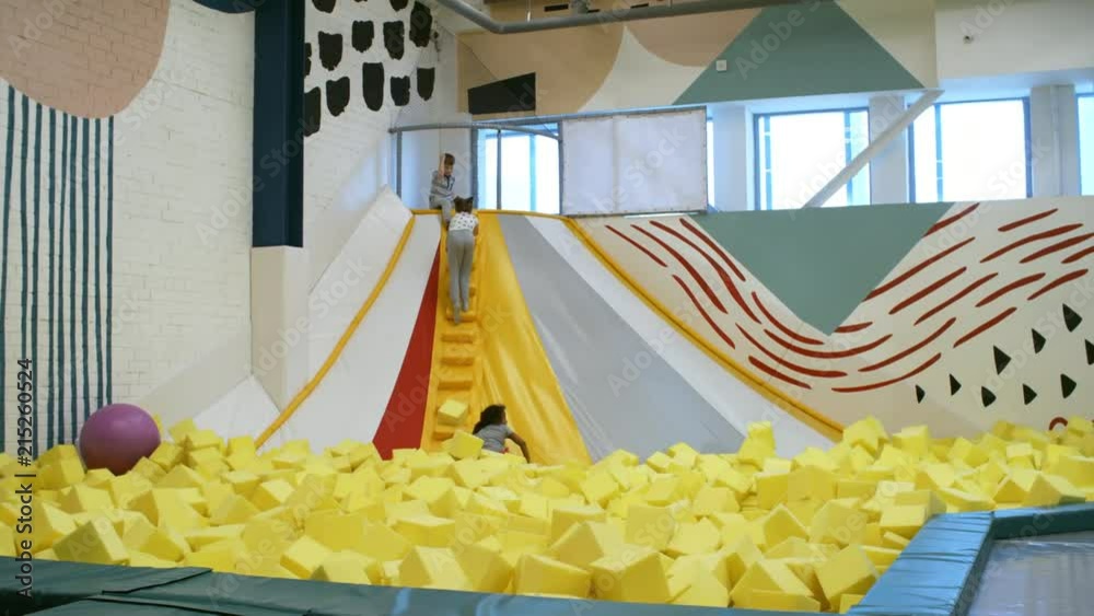 Wall mural four young children of different ethnicities climbing stairs of inflatable structure in playroom and