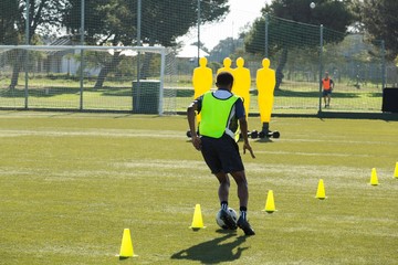Soccer player dribbling through cones