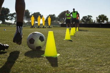 Soccer player dribbling the ball through cones
